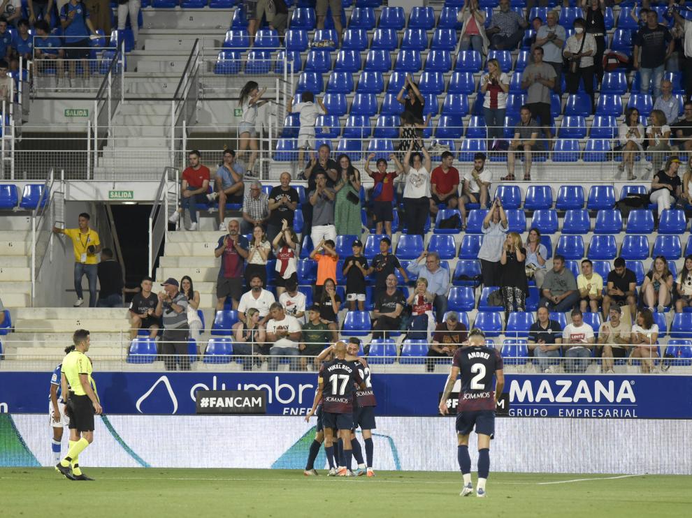 Los jugadores del Huesca celebran uno de sus tres goles ante la Real Sociedad B con una grada poco poblada al fondo.