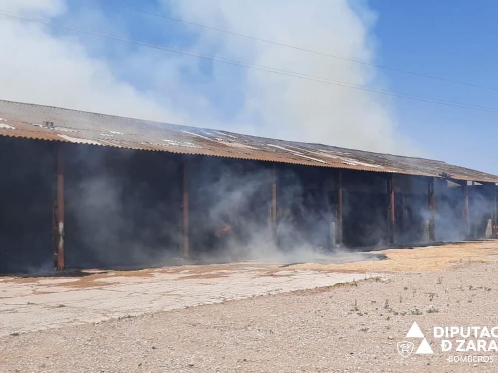 Los bomberos de la DPZ trabajan en sofocar un incendio en un almacén de paja de La Joyosa