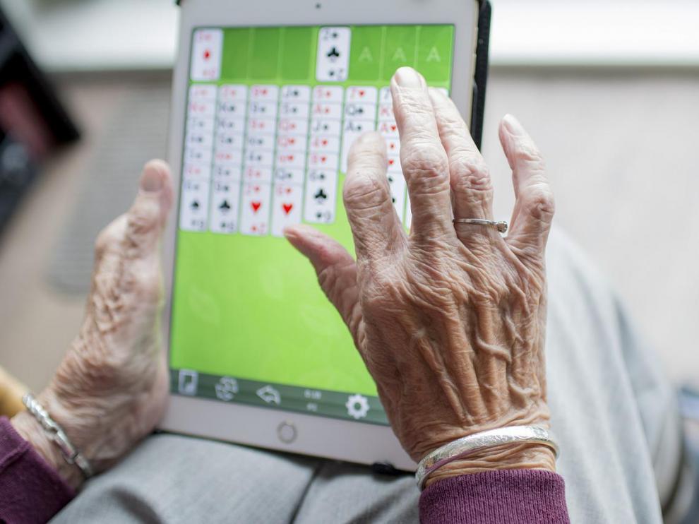 Foto de archivo de una anciana jugando a un juego en una tablet