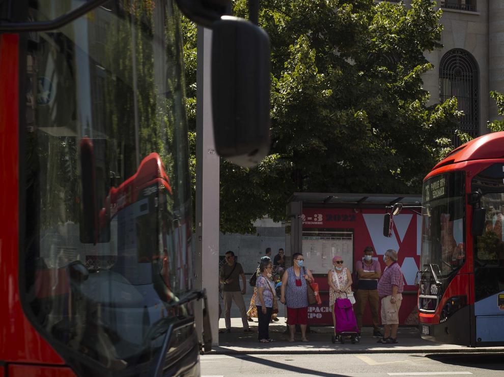 Varios usuarios esperan al autobús, resguardados a la sombra, en una marquesina de la plaza de España, ayer.