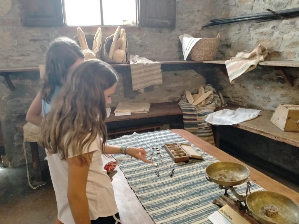 Dos niñas observan los instrumentos que se utilizaban en la elaboración del pan.