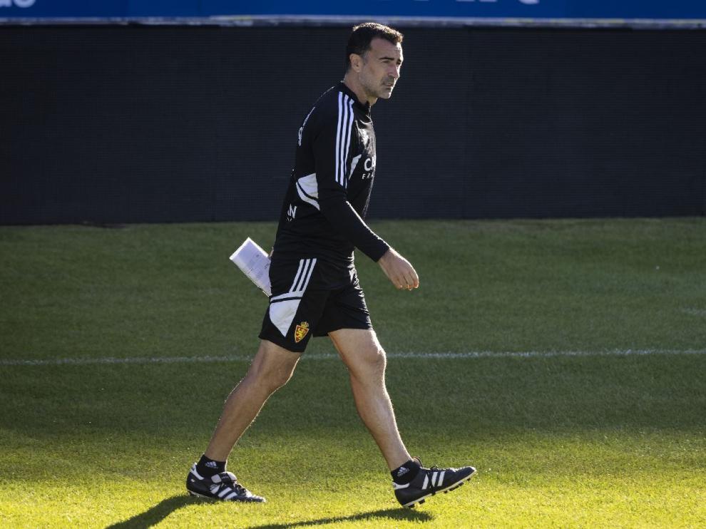 Juan Carlos Carcedo, apuntes en mano, camina entre sol y sombra con gesto serio antes de entrenamiento del Real Zaragoza en La Romareda.