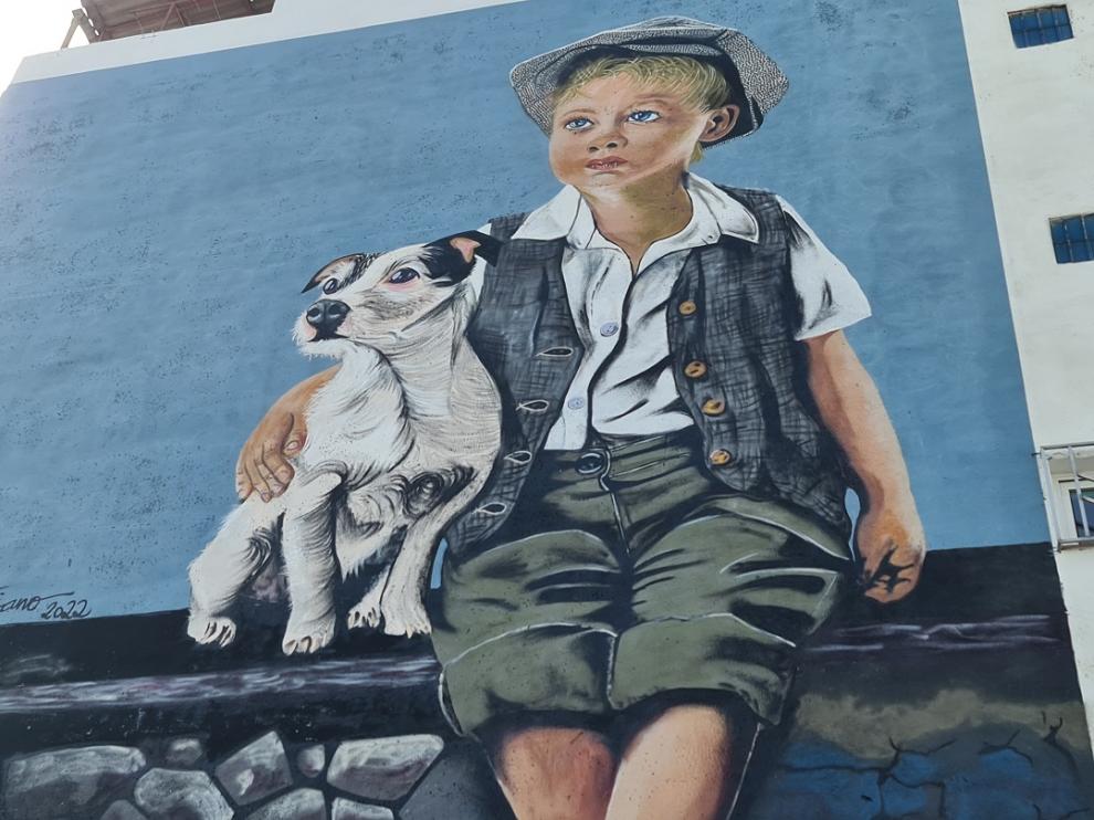 Txus Montejano ha pintado un niño con un perro en un edificio que se halla en la salida de Binéfar hacia San Esteban de Litera.
