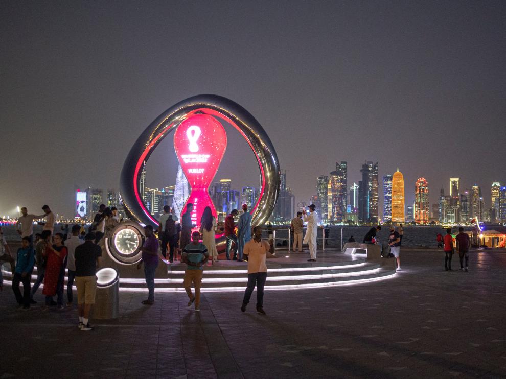 Varios ciudadanos en Doha ante una escultura conmemorativa del Mundial