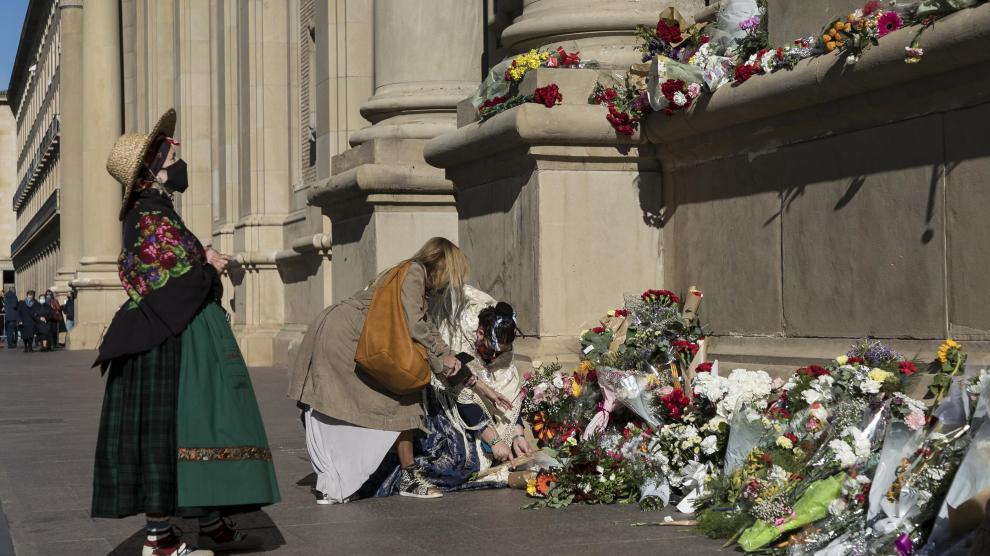Algunas personas se acercaron ayer al conjunto escultórico de la fachada del Pilar a depositar ramos de flores.