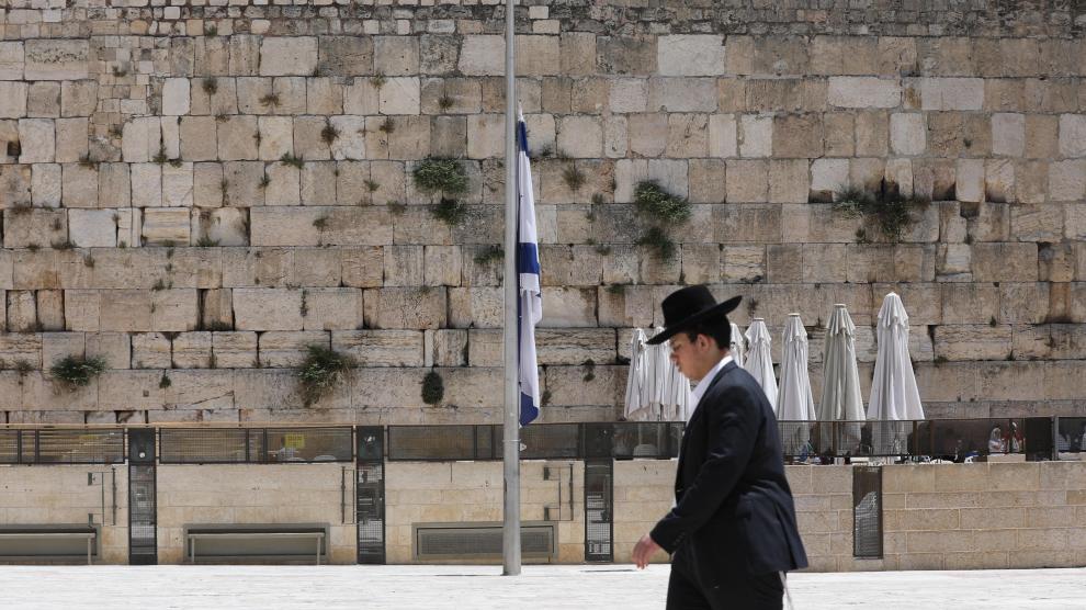 Un judío ultraortodoxo pasa delante de una bandera a media asta en Jerusalén