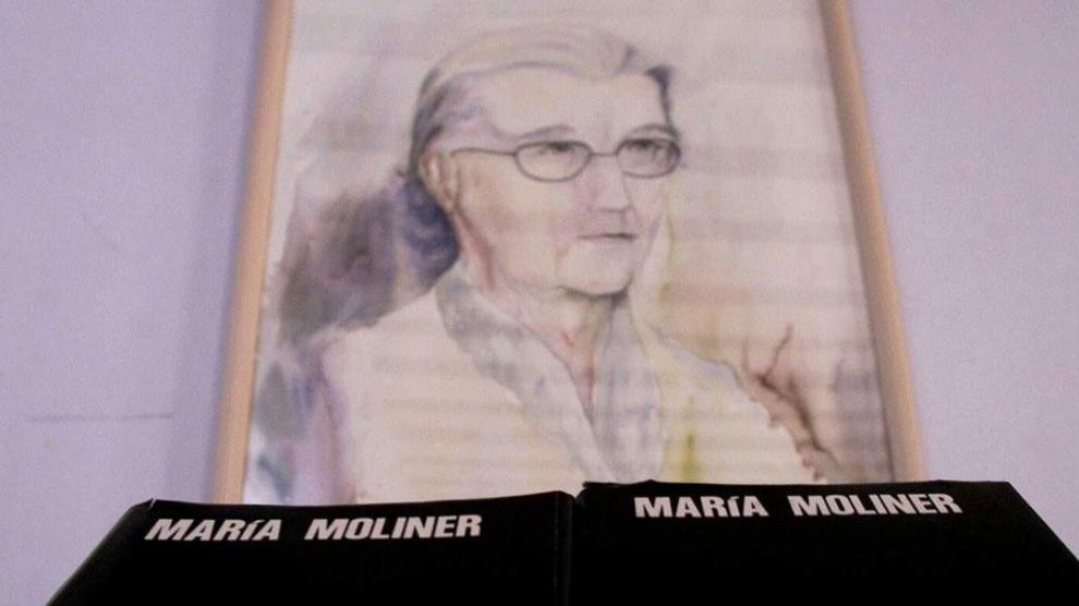 Un ejemplar del Diccionario de Uso del Español, junto a un retrato de María Moliner, en la biblioteca de Paniza.
