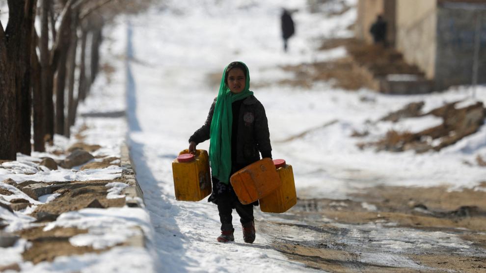 Una niña con bidones para recoger agua en una calle nevada en Kabul