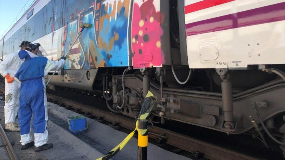 Operarios limpian una de los trenes vandalizados con grafitis.