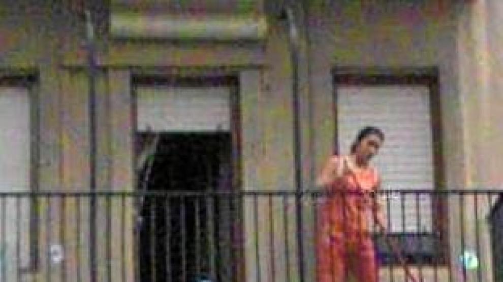 Limpiando en la plaza de San Pedro Nolasco, en Zaragoza. Una mujer barre un balcón. Aun con el rostro difuminado, su silueta permite reconocerla.