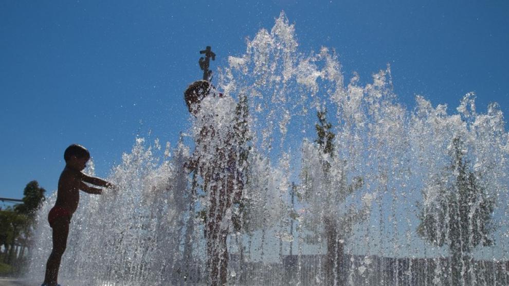 Un grupo de niños se refresca en una fuente