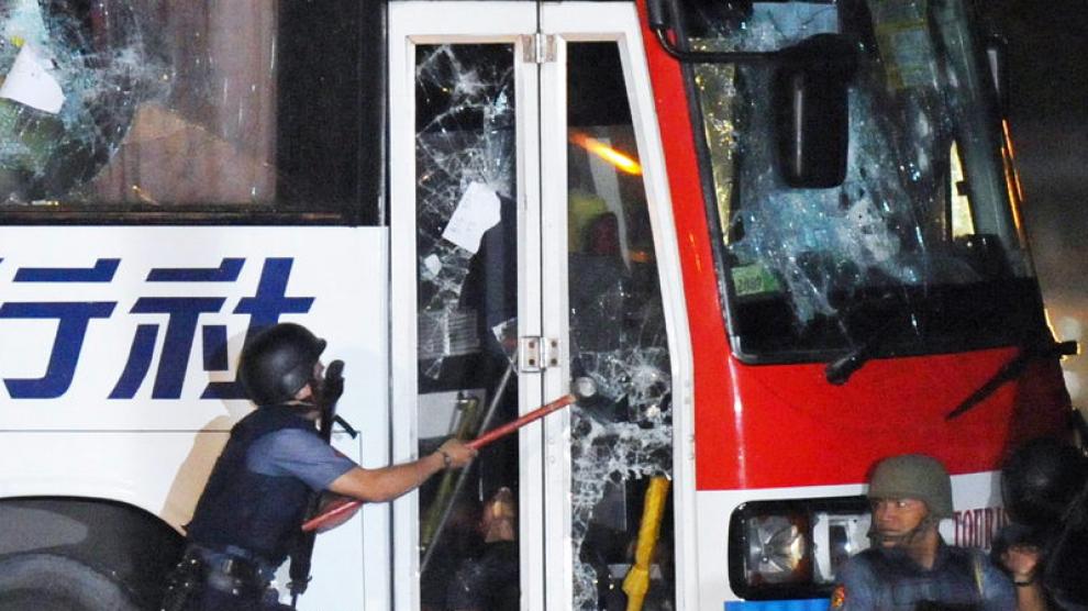 Un policía rompe el cristal de la puerta del autobús durante el tiroteo.