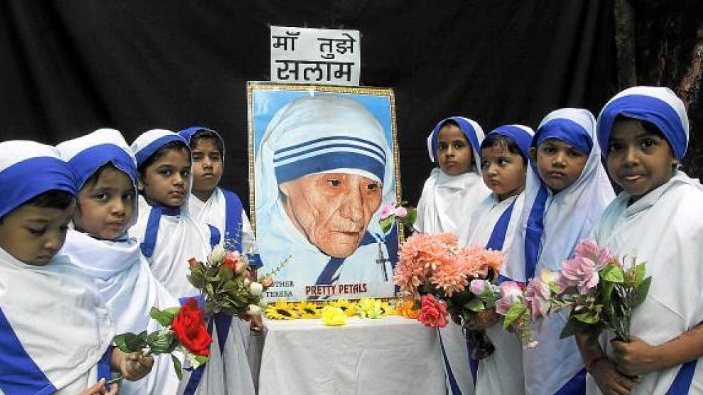 Niñas vestidas como Misioneras de la Caridad realizan una ofrenda floral en India, ayer.