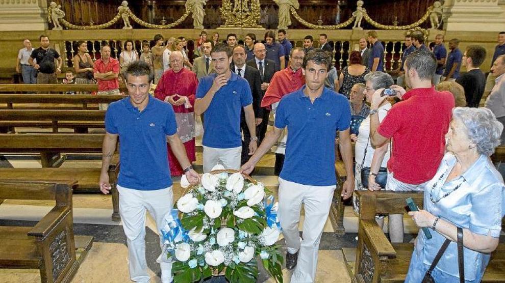 Los capitanes del Real Zaragoza, Gabi, Jorge López y Poncio, seguidos por la directiva y el capellán, llevan las flores al altar.