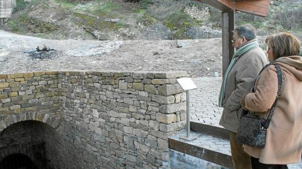 Unos visitantes observan la entrada al pozo moro, sobre la que se ha construido una pérgola.
