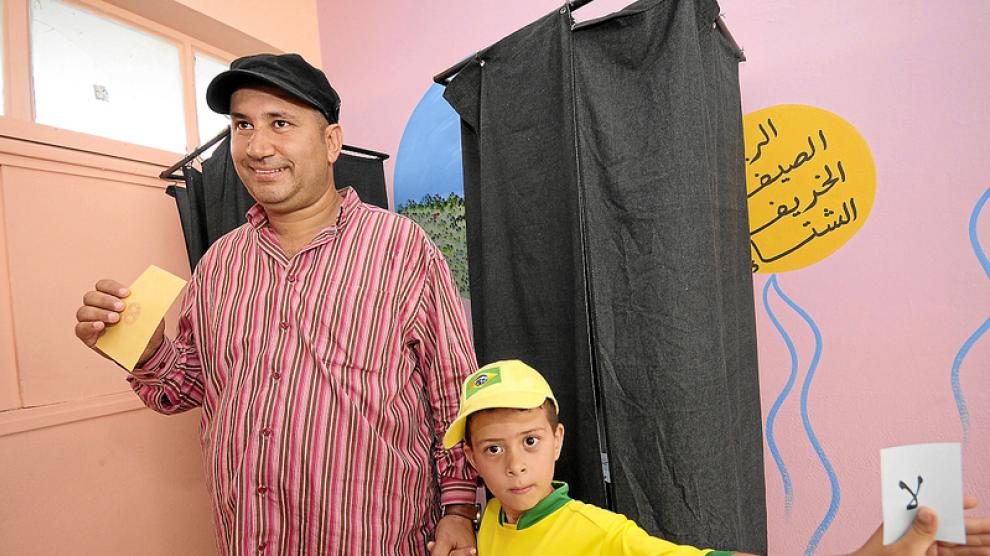 Un marroquí acude a votar mientras su hijo muestra una papeleta del 'no'.