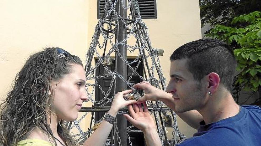 Una pareja sella su amor colocando un par de candados en el árbol del monasterio.