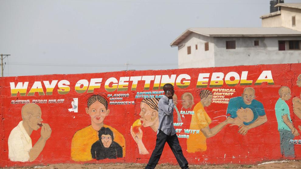 Un ciudadano de Liberia pasea por delante de un mural divulgativo pintado para concienciar sobre la epidemia de ébola.