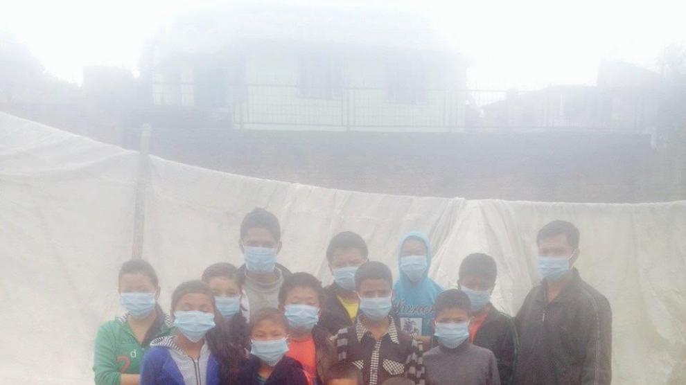 Niños en uno de los centros de acogida de Katmandú se protegen del polvo y el olor