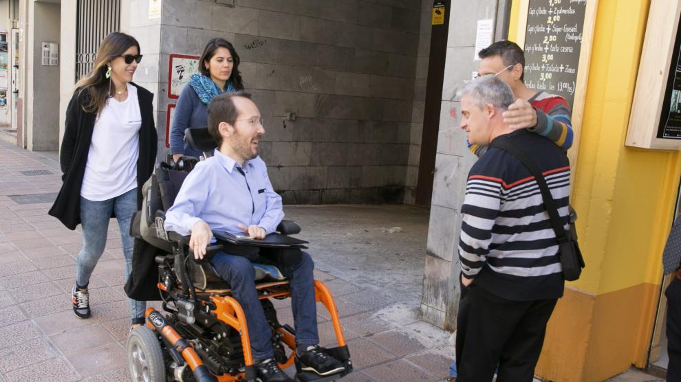 El secretario de Organización de Podemos, Pablo Echenique, saluda a unos ciudadanos en su camino hacia la rueda de prensa