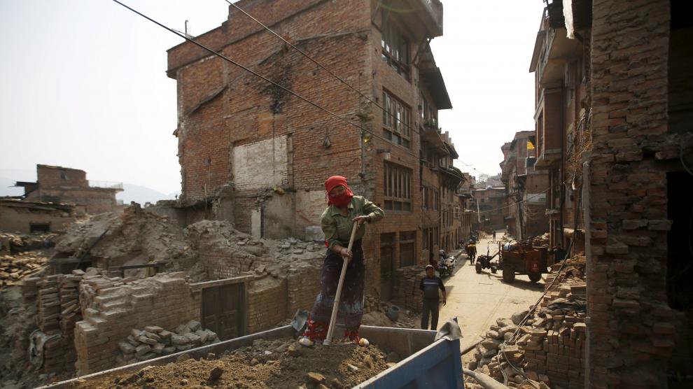 Una mujere trabaja en la reconstrucción de una vivienda en Nepal, un año después del terremoto.