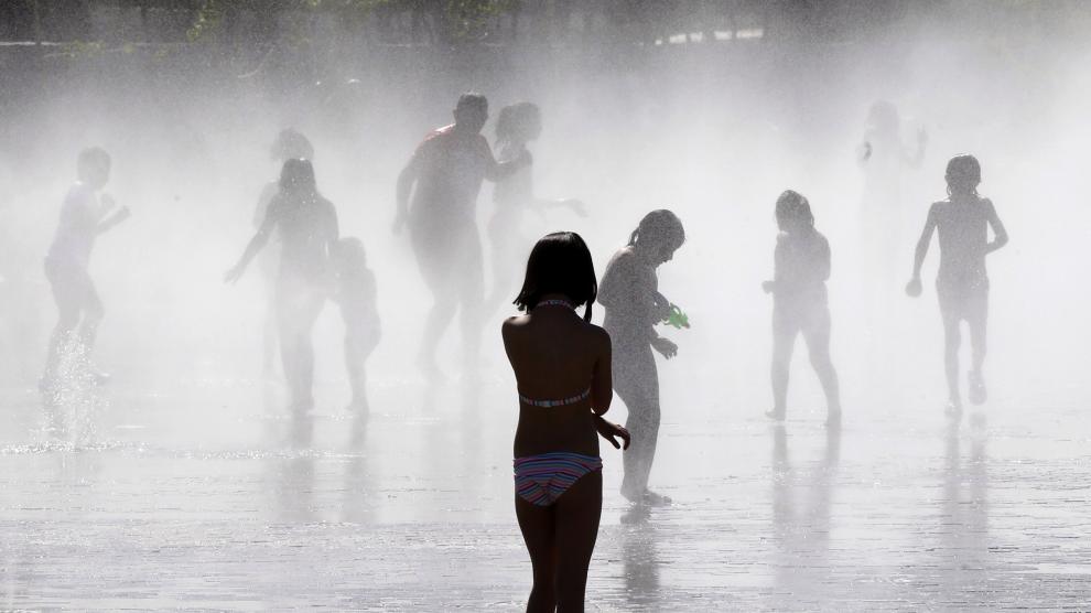 Cuando arrecia el calor, nada como refrescarse, como hacen estos niños en una fuente de Madrid.