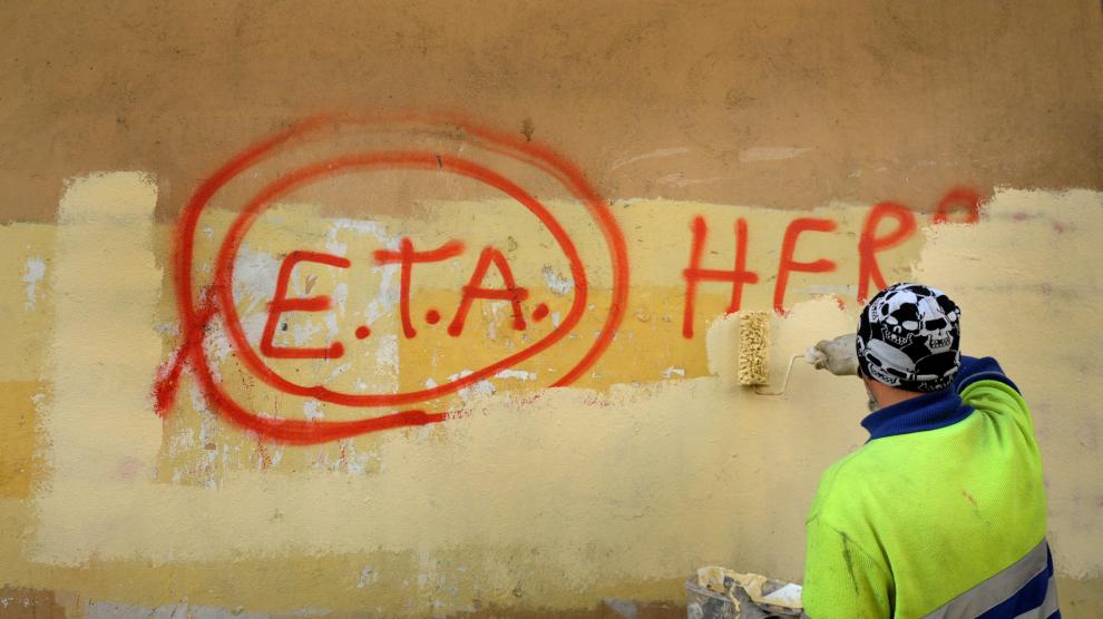 Un operario borra una pintada sobre ETA.