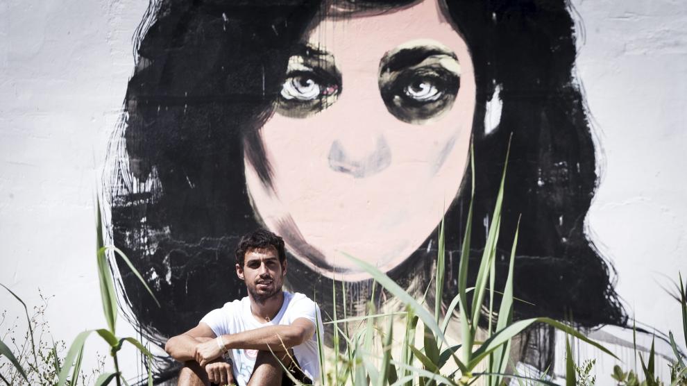Luis Costa, delante del mural que ha pintado la artista castellonense Paula Bonet este verano en Grañén.