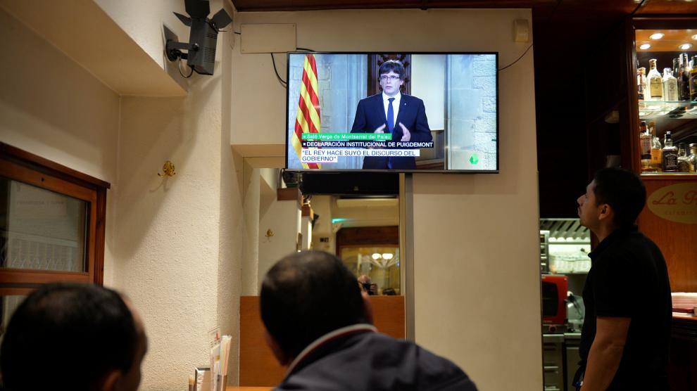 Varios clientes miran la comparecencia de Puigdemont desde un bar de Vic.