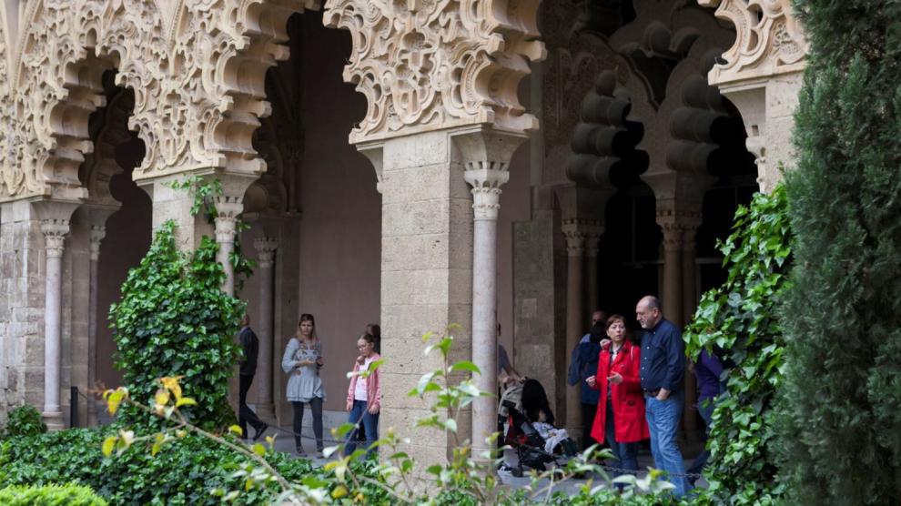 Visitantes bajo los arcos de patio central del palacio de la Aljafería, en Zaragoza.