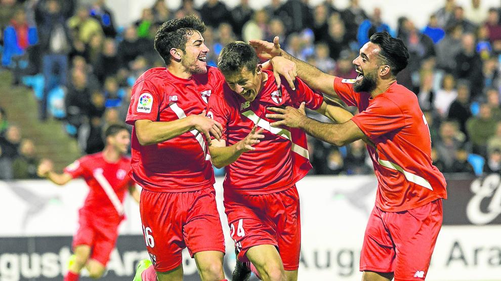 Marc Gual, en el centro, recibe la felicitación de dos compañeros del Sevilla Atlético tras marcar hace un año en La Romareda.