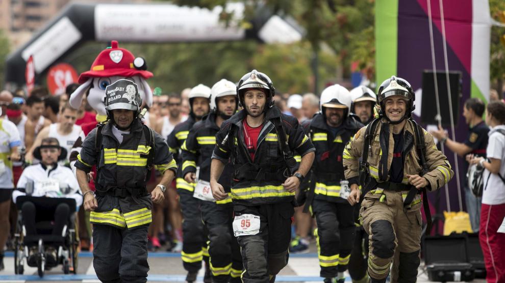 Imagen de los bomberos, con el equipo a cuestas, durante la 10K Bomberos de Zaragoza.