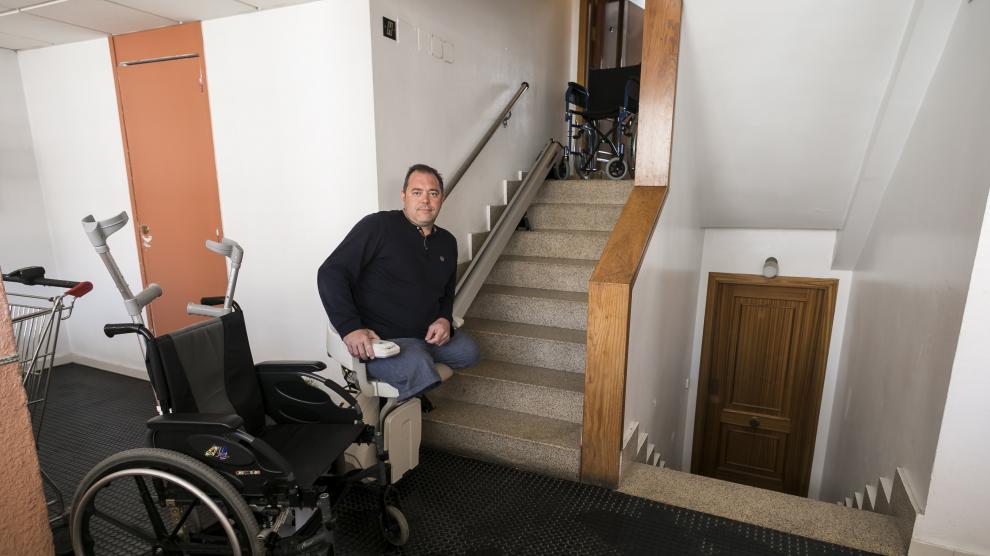 Eugenio, en la silla elevadora que tuvo que instalar para poder acceder a su vivienda.