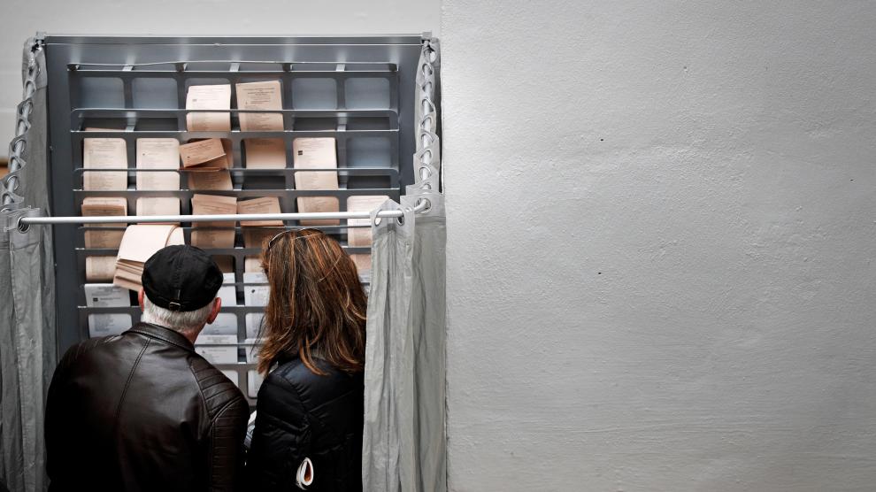 Dos personas eligen sus papeletas para votar en un colegio electoral de España.