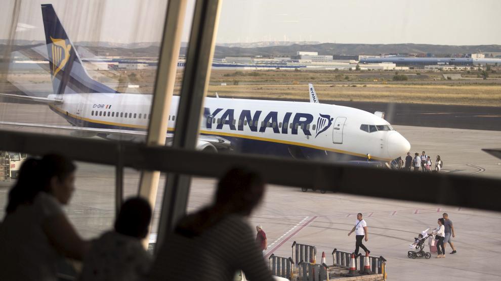 Un grupo de pasajeros observan un avión de Ryanair desde los ventanales del aeropuerto de Zaragoza.