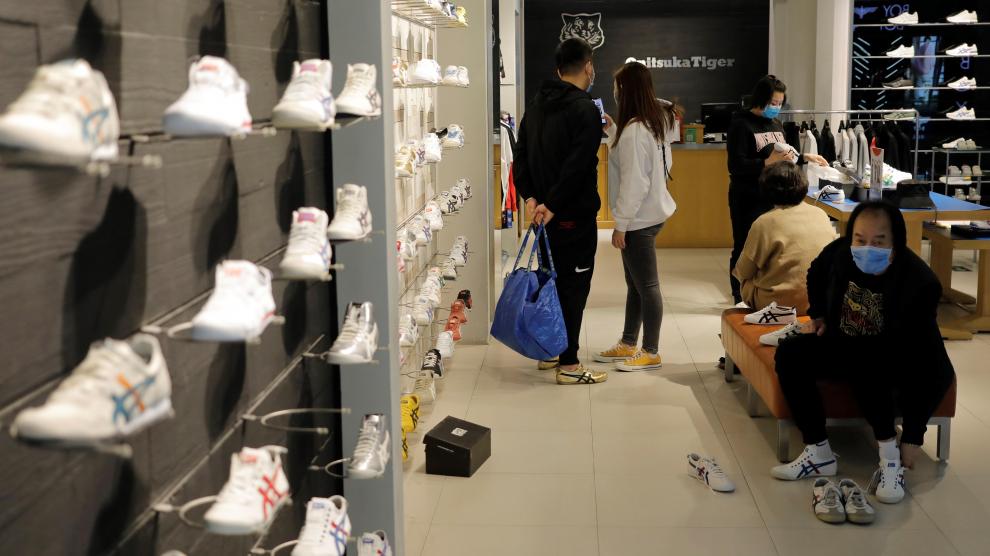 Personas con máscaras faciales compran este viernes en una zapatería de un centro comercial en Pekín.