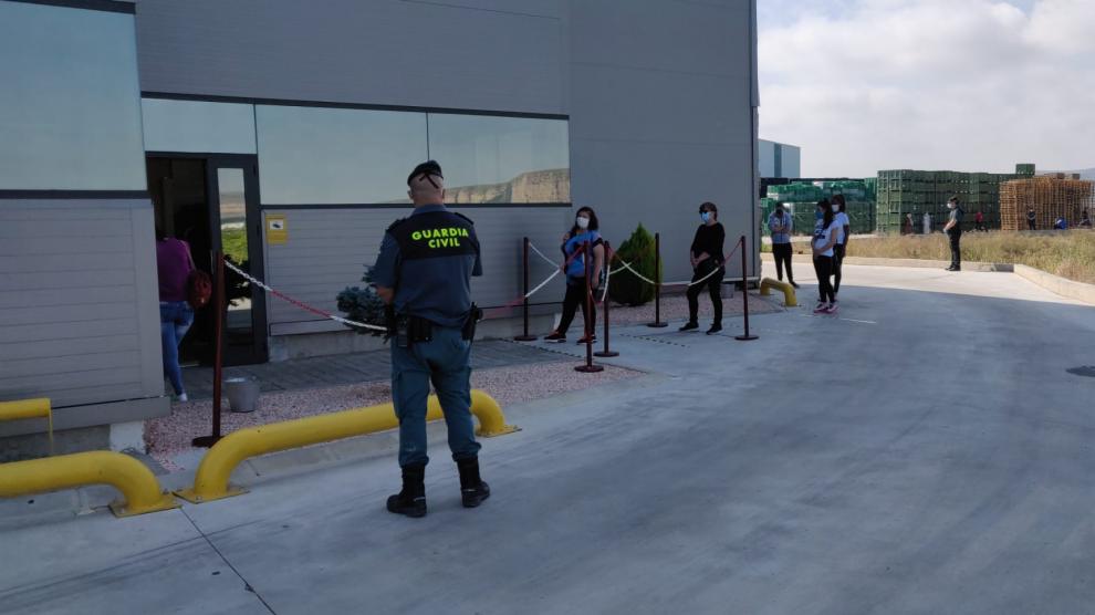 Los trabajadores guardan cola manteniendo la distancia de seguridad frente a las instalaciones de la empresa.