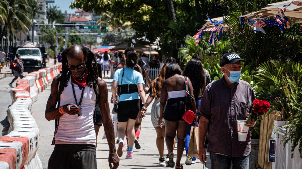 Personas con y sin mascarilla pasean por Miami Beach (Florida).