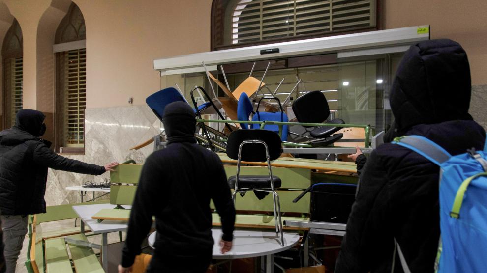 A demonstrator in support of rap singer Pablo Hasel uses a table to set up a barricade against a door of the rectory of Lleida University after Hasel was sentenced to jail time of charges of glorifying terrorism and insulting the Spanish Crown and state institutions, in Lleida, Spain February 15, 2021. REUTERS/Lorena Sopena    NO RESALES. NO ARCHIVES    REFILE - QUALITY REPEAT[[[REUTERS VOCENTO]]] SPAIN-RIGHTS/RAPPER