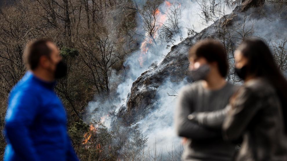 Varias personas observan este domingo en Endarlatsa (Guipúzcoa) un foco del incendio forestal.
