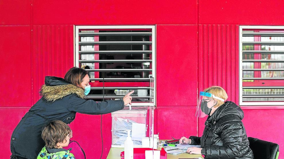 Una mujer vota en la secretaría del colegio Marie Curie de Zaragoza instalada en el porche de infantil.