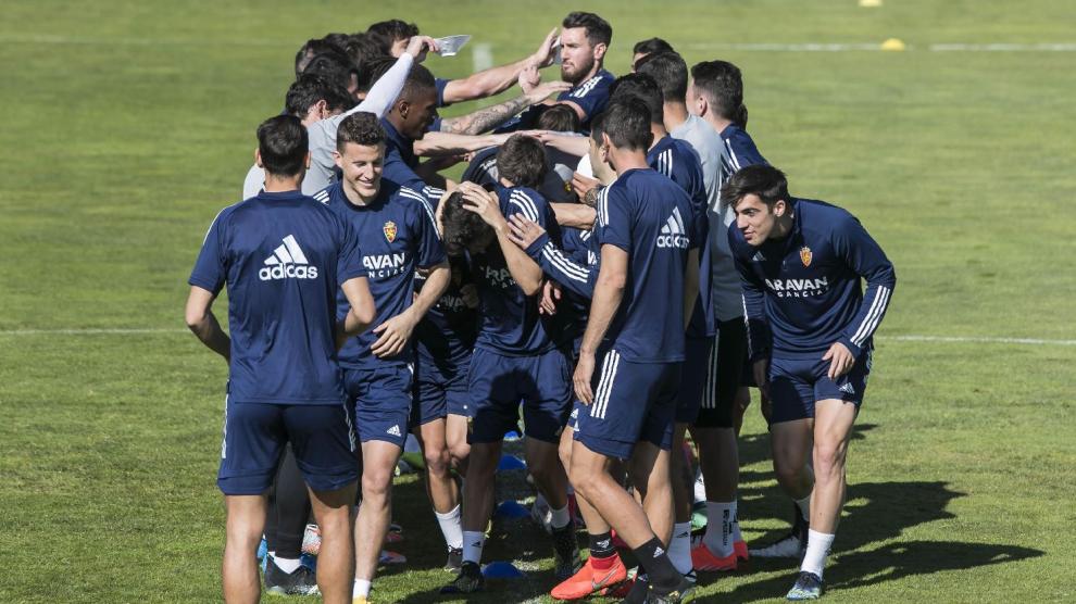 Los jugadores del Real Zaragoza, en una piña de castigo para los perdedores en un ejercicio táctico, dentro del buen ambiente que reina en el grupo.