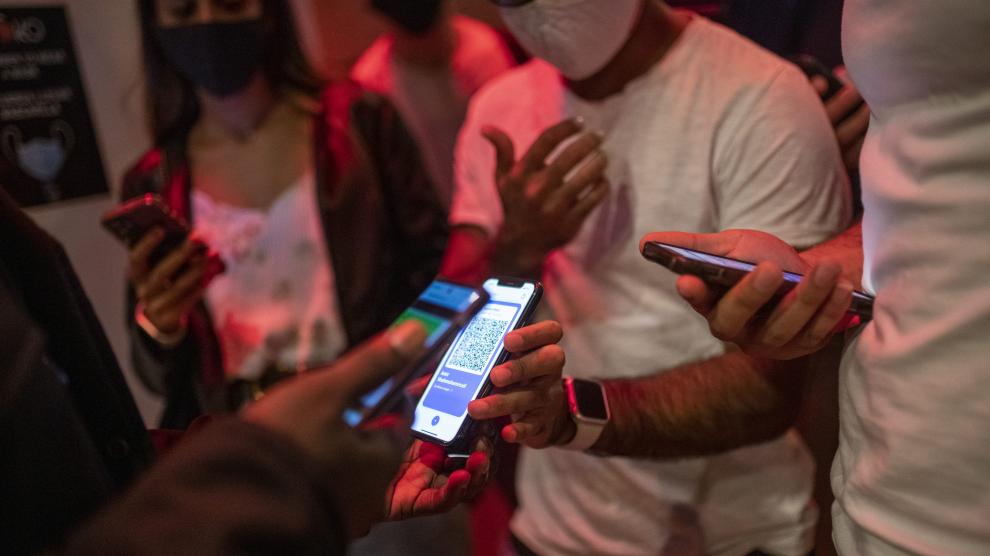 Una persona muestra su pasaporte covid en la entrada de una discoteca.