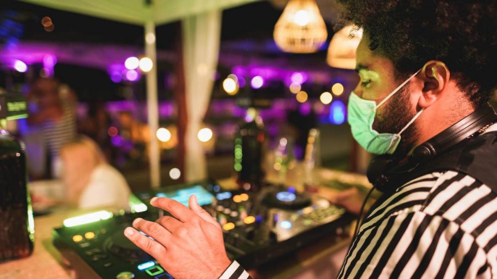 Pinchadiscos con mascarilla en el interior de un pub.