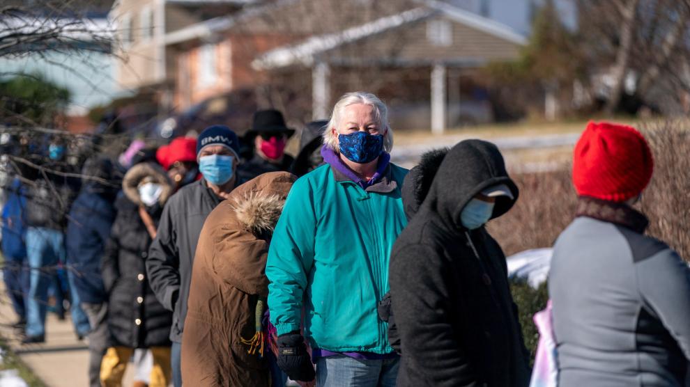 People stand in line to receive free at home COVID-19 Antigen Rapid test kits