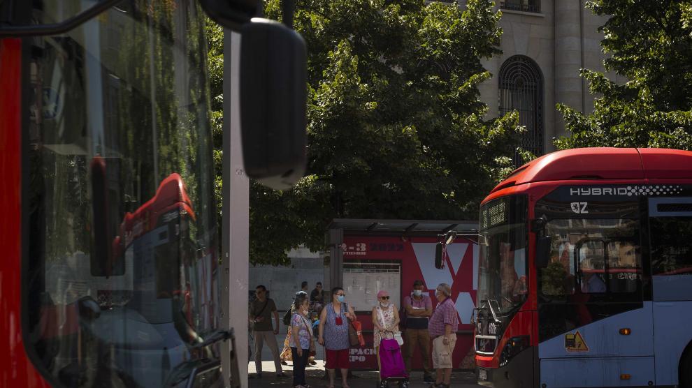 Varios usuarios esperan al autobús, resguardados a la sombra, en una marquesina de la plaza de España, ayer.