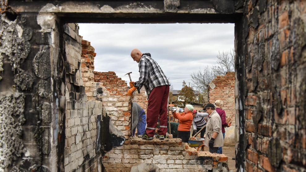 Varios voluntarios colaboran en la reconstrucción de las casas destruidas en el pueblo ucraniano de Novoselivka tras un ataque ruso.