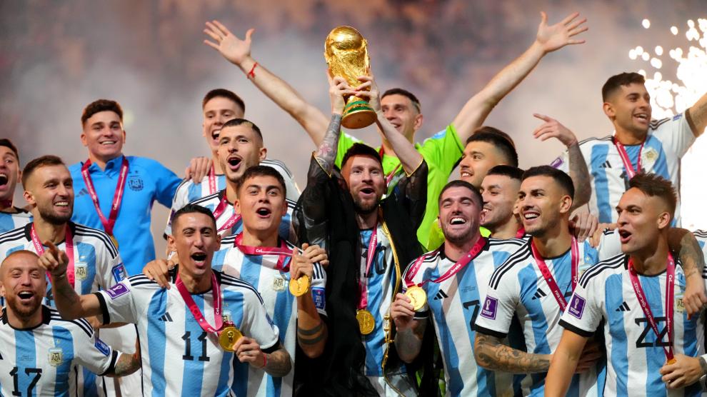 El argentino Lionel Messi sostiene el trofeo de la Copa del Mundo mientras el equipo celebra después del último partido de fútbol de la Copa Mundial de la FIFA Qatar 2022 entre Argentina y Francia en el Lusail Stadium.