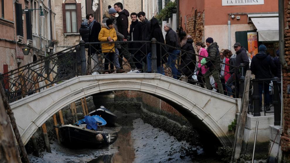Turistas en Venecia pasean por un canal casi seco