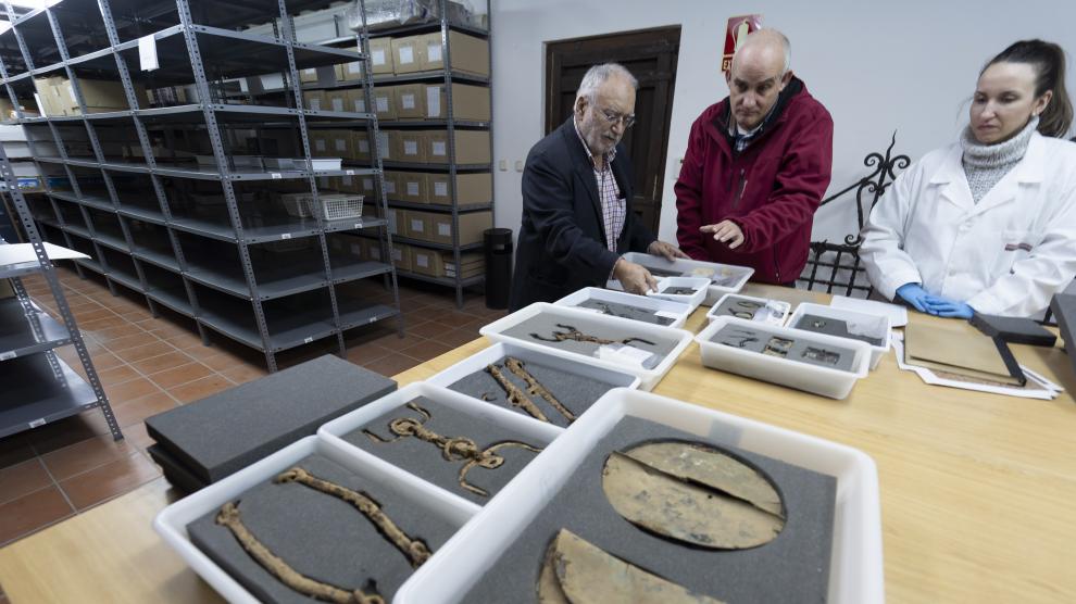 Los arqueólogos Francisco Burillo –izda.– y Raúl Ibáñez, con Elena Almazán, trabajadora del Museo de Albarracín, con armas y objetos de la necrópolis de Bronchales.
